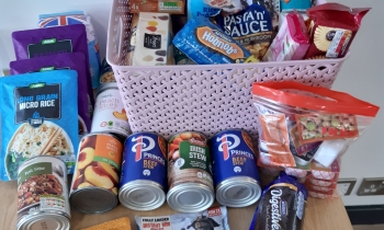 A collection of food is on a table ready to be taken to a food bank
