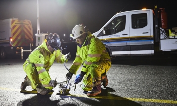 Heathrow airport resurfacing shot at night. Workers in yellow PPE