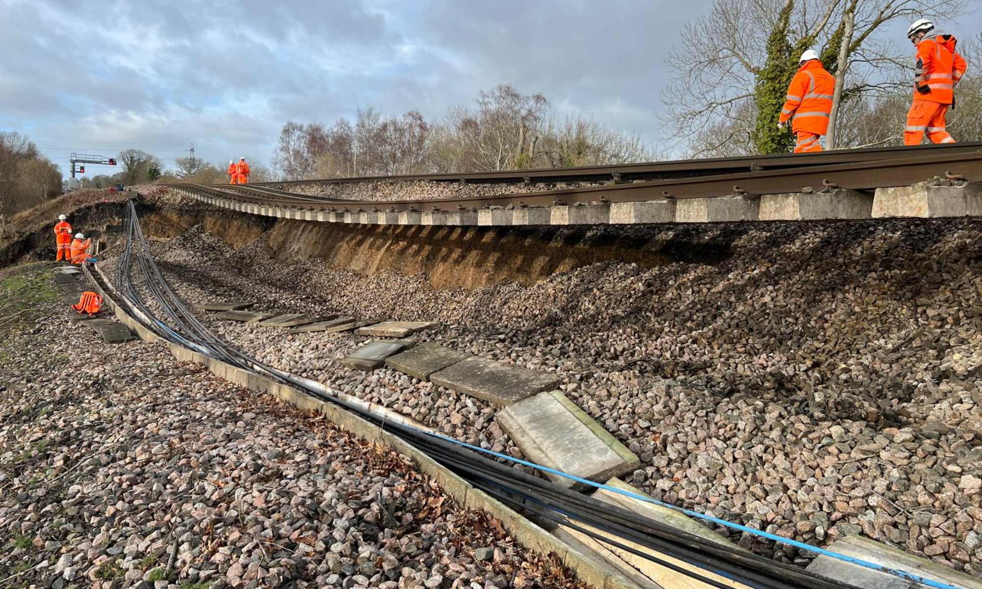 Construction workers wearing orange high vis observing track at Hook