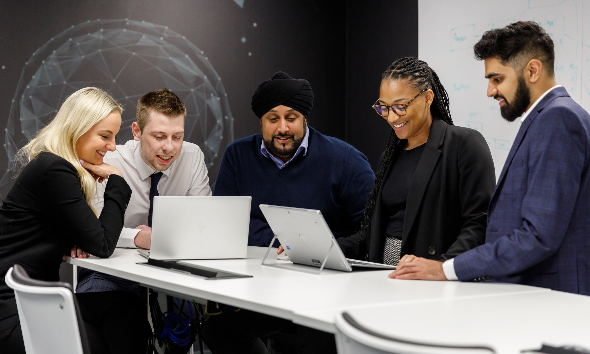 Group of people look at laptops in office